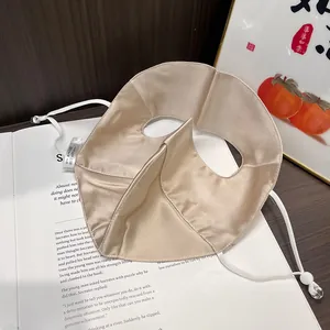 Detail of champagne silk sun mask with adjustable straps on a vintage book