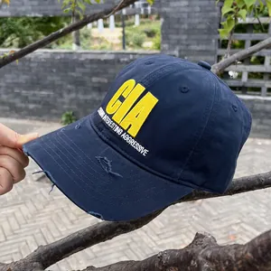 Detail of vintage navy baseball cap with yellow CIA embroidery and distressed torn brim