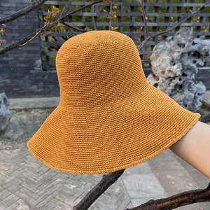 Detail eines ingwergelben handgehäkelten Sonnenhuts aus feinem Stroh im Garten