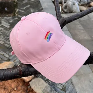 Detalle del bordado de arcoíris y la textura de algodón rosa en una gorra de béisbol