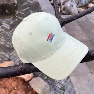 Primer plano de gorra de algodón verde claro con bordado de arcoíris y ojales metálicos