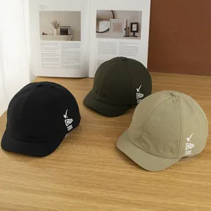 Drie kleuren sneldrogende baseballpetten met korte rand op een rustieke houten tafel