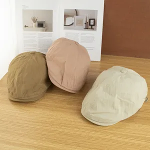 Detail von drei schnelltrocknenden Schiebermützen in Khaki, Rosa und Beige auf Holz