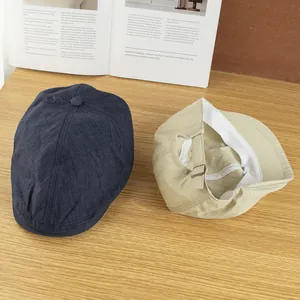 Leichte, schnell trocknende Schirmmützen in Marine und Khaki auf einem Holztisch mit Magazin