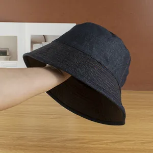 Detailed view of dark blue denim bucket hat with decorative orange contrast stitching