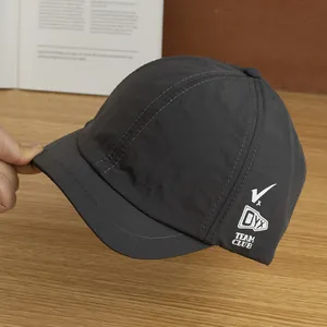 Detail van donkergrijze sneldrogende baseballpet met korte rand van 3 cm en wit borduursel