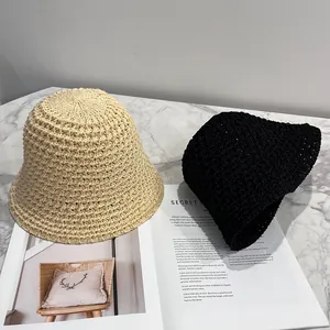 Detail of beige and black hollow-knit sun hats on a stylish marble surface background