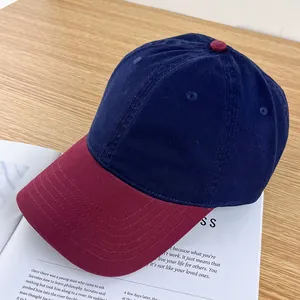 Detail of two-tone cotton baseball cap with navy crown and burgundy brim on a table