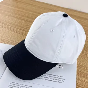Detail of white and black contrast baseball cap with breathable eyelets on wooden desk
