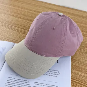 Detail view of a contrast-color baseball cap in lilac canvas with a beige brim on a book