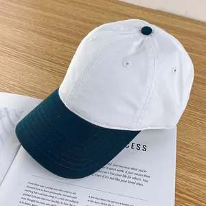 Top view of a two-tone white and dark green cotton baseball cap on a wooden table