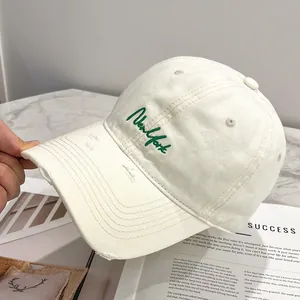 Dettaglio del berretto bianco sporco con ricamo New York verde e visiera stile vintage