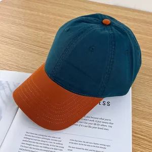 Detail shot of a contrast baseball cap in dark green and orange on a wooden surface