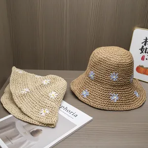 Detail of handmade straw sun hats with daisy embroidery in beige and coffee colors