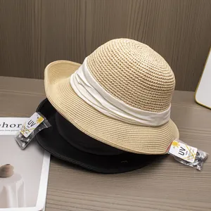 Détail de chapeaux de paille tressés beige et noir avec étiquettes anti-UV