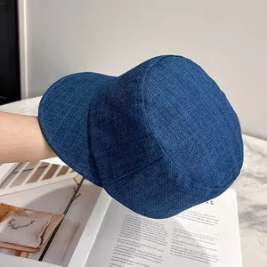 Detailed texture of navy linen newsboy cap held over a vintage magazine background