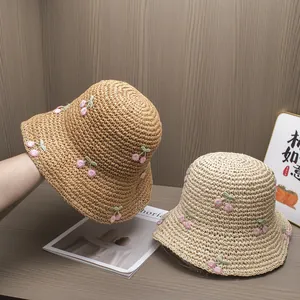 Detail of hand-woven straw hats featuring exquisite pink cherry embroidery and mesh texture