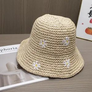 Detailed close-up of small daisy embroidery on a breathable beige woven straw sun hat