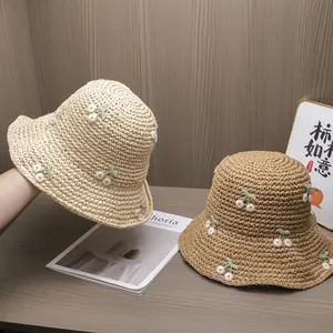 Detailed straw bucket hats with cherry embroidery in beige and light brown tones