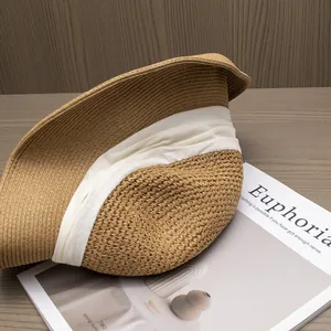 Gros plan d'un chapeau de paille avec ruban crème sur une surface en bois naturel