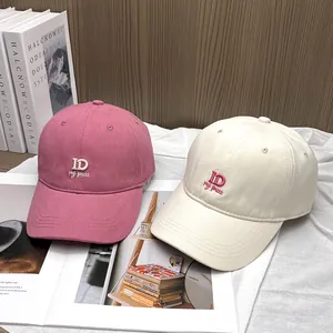 Pink and cream baseball caps with ID embroidery on wooden and magazine background