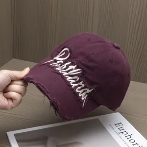 Dettaglio del ricamo e dei fori usurati sul cappellino da baseball in cotone bordeaux