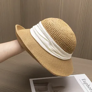 Détail d'un chapeau de paille kaki tissé avec un ruban élégant en tissu plissé blanc