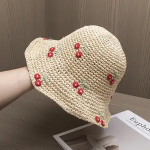 Detail of hand-woven straw hat featuring 3D embroidered cherries and fine crochet texture