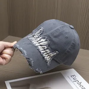 Dettaglio del cappello da baseball grigio scuro con ricamo di lettere e bordi logori
