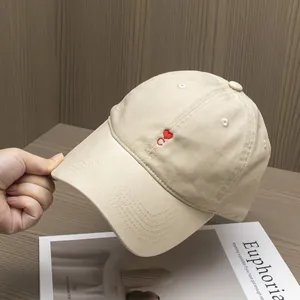 Close-up of heart and C letter embroidery on beige cotton baseball cap with curved brim