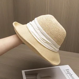Détail d'un élégant chapeau de paille avec un large ruban en tissu plissé blanc et texture tissée