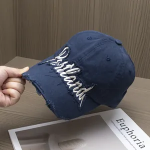 Dettaglio dei bordi sfrangiati e del ricamo bianco su un cappellino in cotone blu notte