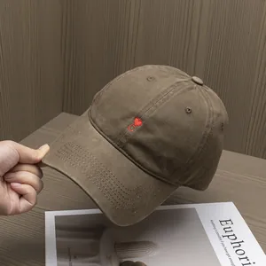 Close-up of heart and C letter embroidery on a brown cotton baseball cap