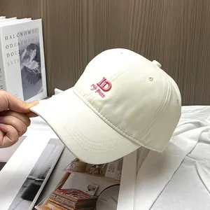 Detailed pink ID letter embroidery on cream cotton baseball cap with curved brim