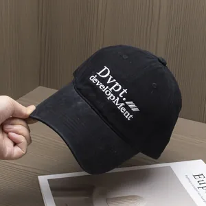 Gros plan de la broderie blanche sur une casquette en coton noir posée sur une table en bois
