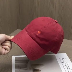 Detailed close-up of dark red cotton baseball cap featuring small heart embroidery