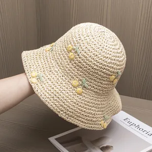 Detail of beige handmade straw hat with exquisite cherry embroidery and woven texture
