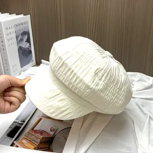 Detailopname van de crèmewitte baret met unieke rimpeltextuur en hoogwaardige stofkwaliteit