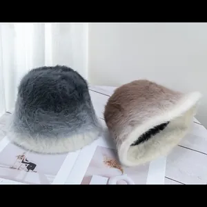 Detail of plush faux fur bucket hats in gradient grey and brown on white wood surface