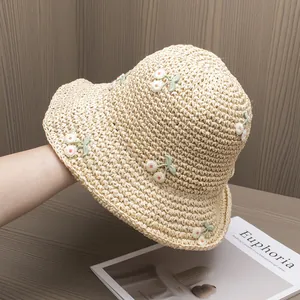 Detailed close-up of handmade straw sun hat featuring delicate pink cherry embroidery