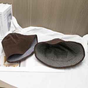 Detail view of brown corduroy bucket hat showing blue plaid lining and stitching