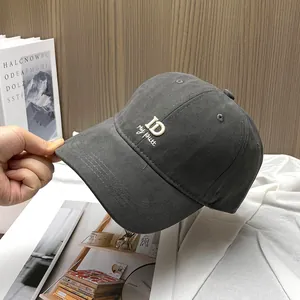 Detail of dark grey baseball cap featuring white ID letter embroidery and twill texture