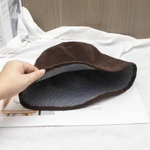Detail of dark coffee suede bucket hat showing blue and white plaid lining texture