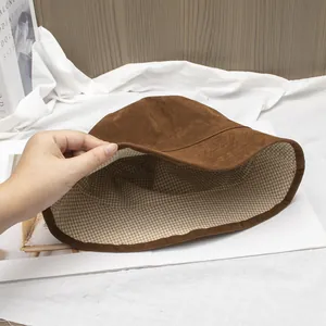 Detail of brown faux suede bucket hat showing the beige plaid fabric lining texture