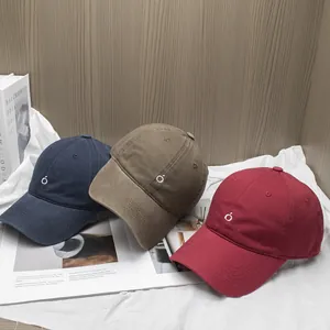 Minimalist cotton baseball caps in navy, khaki, and burgundy with circle embroidery