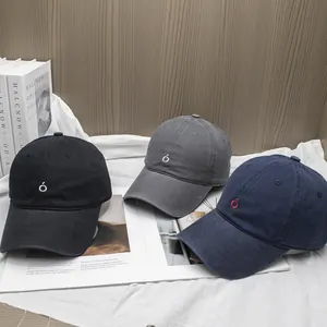 Detailed view of three cotton baseball caps with embroidered letters in a lifestyle setting