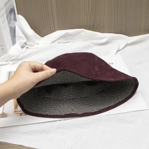 Detail view of burgundy faux suede bucket hat with black and white checkered lining