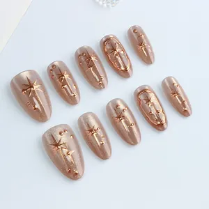 Champagne cat eye press-on nails with rose gold star motifs in almond shape