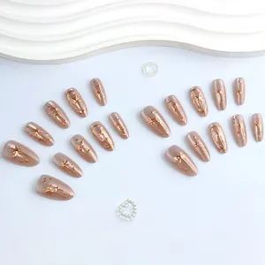 Champagne cat eye press-on nails with rose gold star accents and 3D metallic textures