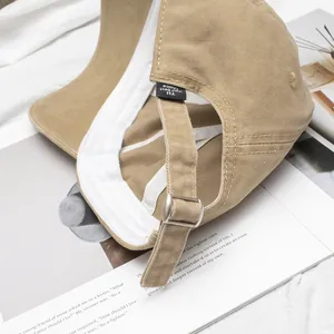 Detail view of khaki cotton baseball cap featuring adjustable silver metal buckle and interior tag